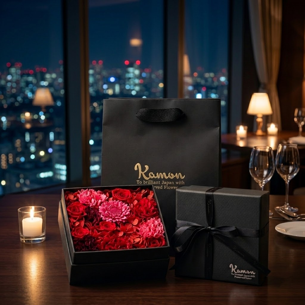 夜景の見えるテーブルに置かれた、赤とピンクのプリザーブドフラワーのギフトボックスとKamonのショッパー|FLOWER KAMON